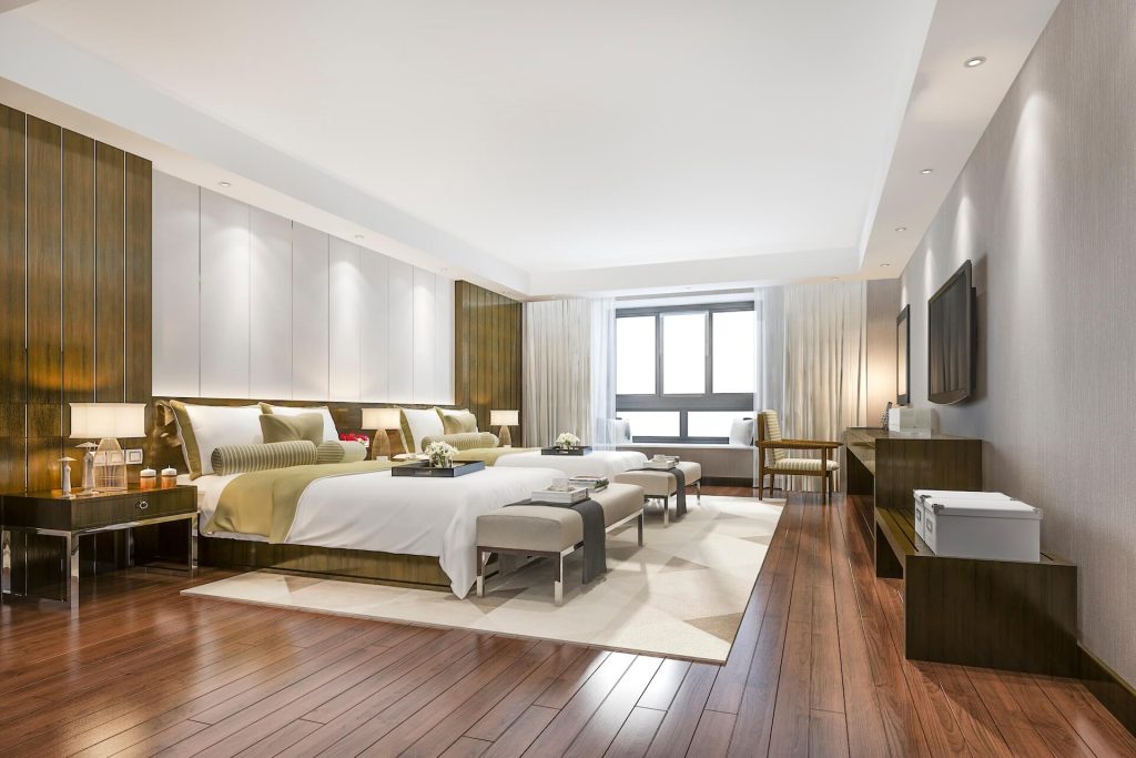 Modern room with two beds and hardwood flooring | Featured image for the full house renovation company page of Collaborate Construction.