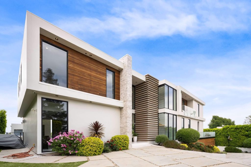 Large new house with lush greenery surrounding it | Featured image for the full house renovation company page of Collaborate Construction.