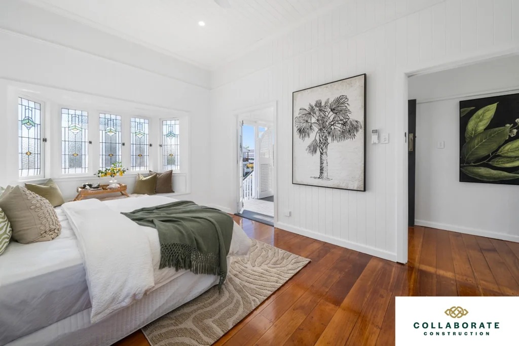 New bedroom with wooden floors, white panelled walls and several paintings on the walls | Image for the Rooming House Builders page.